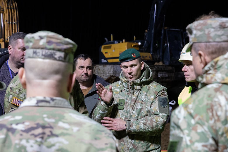 A Lithuanian Armed Forces officer discusses recovery operations with U.S. Army officers and emergency services personnel, on how to build a sandbag dam during recovery efforts for a U.S. Army M88 Hercules recovery vehicle submerged under several meters of water in a swamp near a training area in Pabradė, Lithuania, March 28, 2025. (U.S. Army photo by Staff Sgt. Joseph Novak)