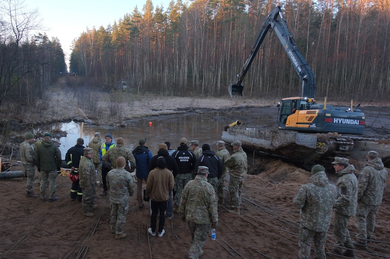 Members of Commander, Task Force (CTF) 68, a U.S. Navy dive team, arrive on site to assess diving operations in support of efforts to find four U.S. soldiers in a submerged M88 Hercules recovery vehicle at a training site near Pabradė, Lithuania, March 29, 2025.