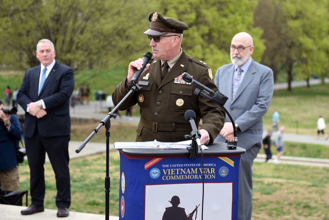 A man in a military uniform stands behind a lectern.