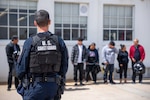 A Coast Guardsman watches a group of aliens line up on Coast Guard Sector San Diego