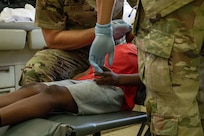 U.S. Air Force Senior Airman Joshua Antonio Moreno, 433rd Aerospace Medicine Squadron dental technician, right, holds a young patient’s hand for comfort while assisting U.S. Air Force Col. Michael Bates, 433rd AMDS dentist, with a teeth cleaning procedure during the Lesser Antilles Medical Assistance Team (LAMAT) 2025 mission at Celina Clouden Smart Hospital, Union Island, Saint Vincent and the Grenadines, March 20, 2025.