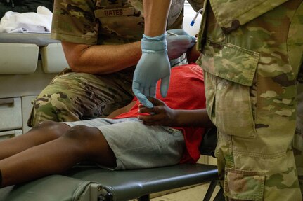 U.S. Air Force Senior Airman Joshua Antonio Moreno, 433rd Aerospace Medicine Squadron dental technician, right, holds a young patient’s hand for comfort while assisting U.S. Air Force Col. Michael Bates, 433rd AMDS dentist, with a teeth cleaning procedure during the Lesser Antilles Medical Assistance Team (LAMAT) 2025 mission at Celina Clouden Smart Hospital, Union Island, Saint Vincent and the Grenadines, March 20, 2025.