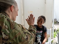 U.S. Air Force Maj. Monica Bentley, 433rd Aerospace Medicine Squadron optometrist, high-fives a young patient after a vision screening during the Lesser Antilles Medical Assistance Team (LAMAT) 2025 health fair at Kingstown, Saint Vincent and the Grenadines, March 20, 2025.