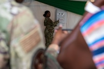 U.S. Air Force Senior Master Sgt. Kashevia Montgomery, 433rd Aerospace Medicine Squadron (AMDS) medical technician, center, conducts an eye exam with an optometry chart while Master Sgt. Stacey Lauterbach, 433rd AMDS optometry technician, left, assists a local resident during a health fair in St. Vincent and the Grenadines, March 19, 2025.