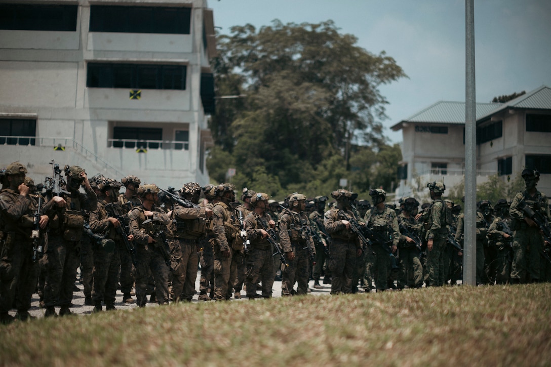 U.S. Marines with 1st Battalion, 5th Marine Regiment, 1st Marine Division, attached to Marine Rotational Force-Southeast Asia, alongside Singapore Guardsmen with 3rd Battalion Singapore Guards, 7th Singapore Infantry Brigade, stand-by for the closing ceremony for Valiant Mark 25 at SAFTI City training facility, Singapore, March 27, 2025. SAFTI City, the premier urban training facility in Southeast Asia, is one of the largest and most technologically advanced facilities of its kind in the world. U.S. Marines with MRF-SEA were the first foreign partner force to train at the facility during Valiant Mark 25. Valiant Mark is an annual, bilateral training exercise designed to enhance interoperability, build mutual defense capabilities, and strengthen military-to-military relationships between the U.S. Marine Corps and Singapore Armed Forces. MRF-SEA is a rotational unit derived from elements of I MEF executing a U.S. Marine Corps Forces, Pacific operational model that involves training events and exchanges with partner military subject matter experts, promotes security goals with Allied and partner nations, and ensures a persistent I MEF stand-in presence west of the international date line. (U.S. Marine Corps photo by Sgt. Shaina Jupiter)