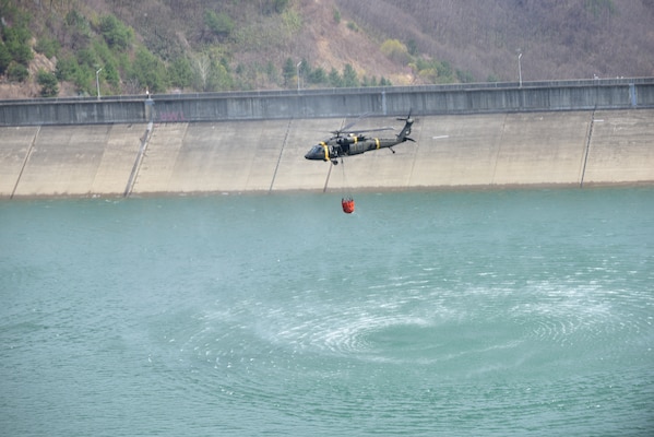 U.S. Forces Korea is assisting efforts to contain wildfires in southeastern regions of the Republic of Korea. In coordination with the ROK Joint Chiefs of Staff and Combined Forces Command, USFK has deployed UH-60 Black Hawk helicopters equipped with Bambi Buckets to support aerial water drop operations. Personnel from the 2nd Combat Aviation Brigade, including pilots and crew chiefs, are actively supporting the mission, with additional assets on standby if needed. (U.S. Army photo by Sgt. Alexander Knight)