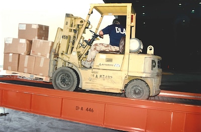A man on a yellow forklift picks up boxes