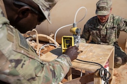 Two Soldiers adjust the chlorination level of the improvised system