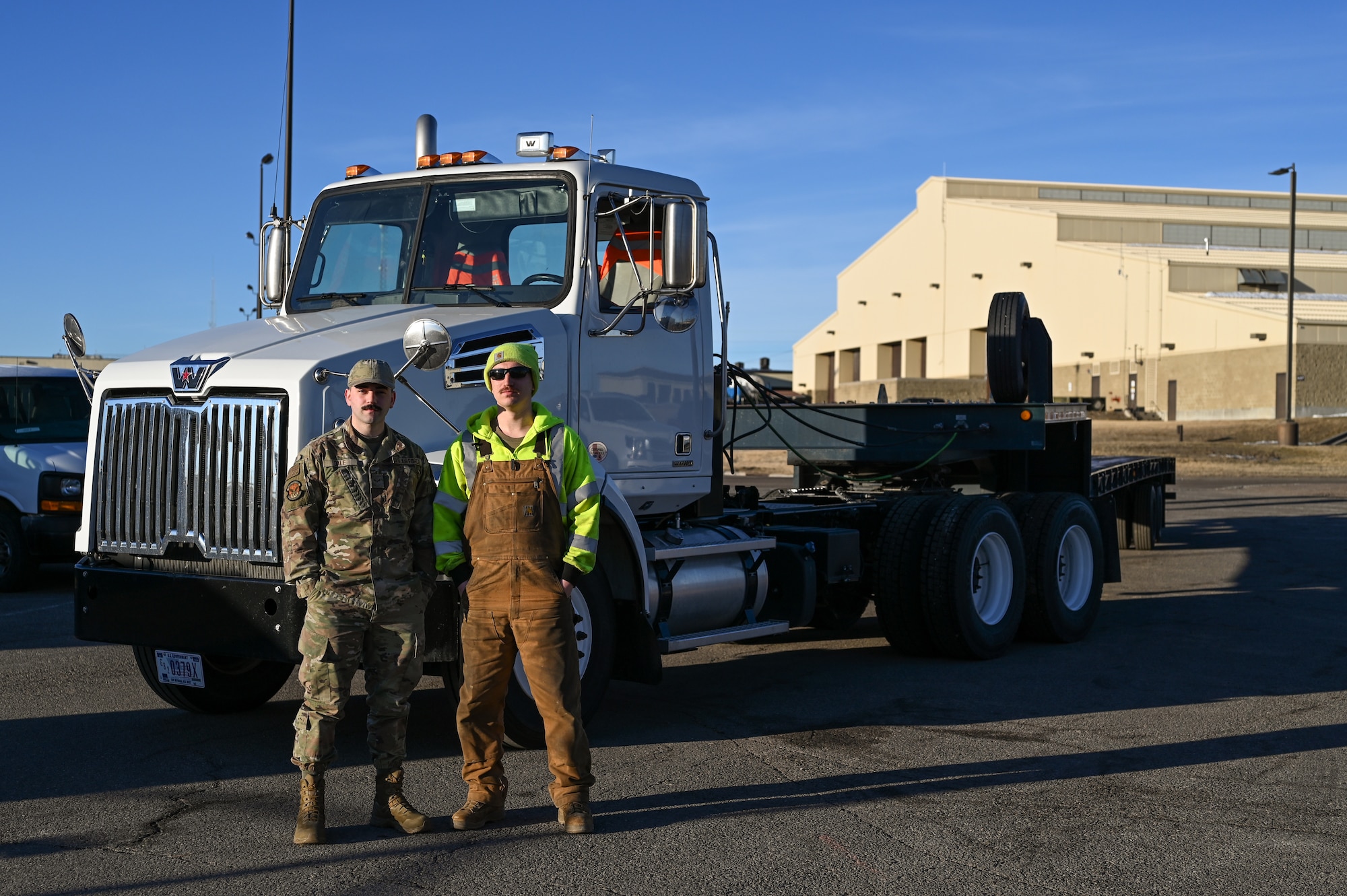 Two Airmen pose in front of a forty-foot tractor truck.