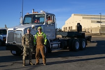 Two Airmen pose in front of a forty-foot tractor truck.