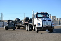 A forklift loads pallets of tires onto a forty-foot flatbed truck.