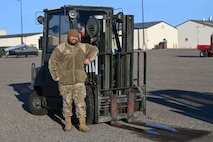 An Airman poses next to a forklift.