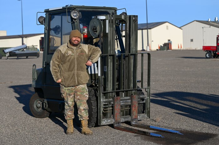 An Airman poses next to a forklift.