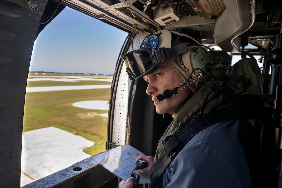 Defense Secretary Pete Hegseth looks out a helicopter window while wearing a flight helmet.