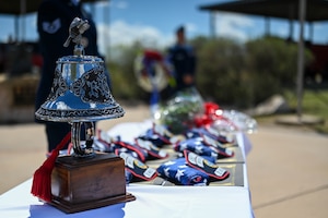Folded flags and the ceremonial bell lay on a table during the annual Department of Defense Fallen Firefighter Memorial Service at the Fire Protection Heritage Pathway, Goodfellow Air Force Base Texas, March 28, 2025. The Fire Protection Heritage Pathway is a memorial that symbolizes the heroism and sacrifice of Department of Defense firefighters who gave their lives in the line of duty (U.S. Air Force photo by Staff Sgt. Nathan Call)