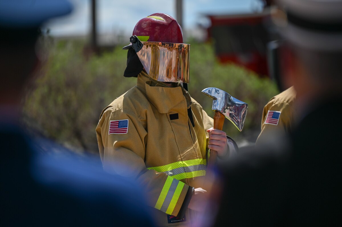 A member of the 312th Training Squadron holds a firefighter's axe during the annual Department of Defense Fallen Firefighter Memorial Service at the Fire Protection Heritage Pathway,, Goodfellow Air Force Base, Texas, March 28, 2025. The ceremony included the firefighters' prayer, a lowering of the flag to half-staff, and the firefighters’ final call. (U.S. Air Force photo by Staff Sgt. Nathan Call)