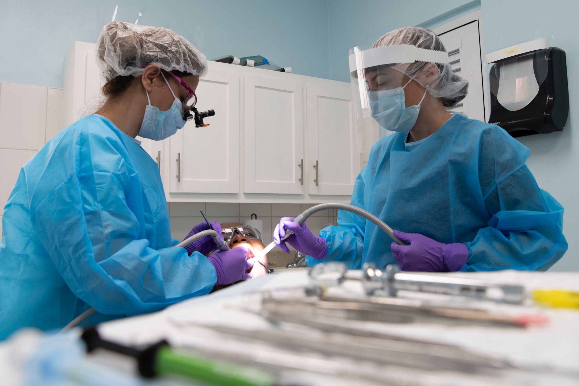 Two military members providing dental treatments during a tooth filling.