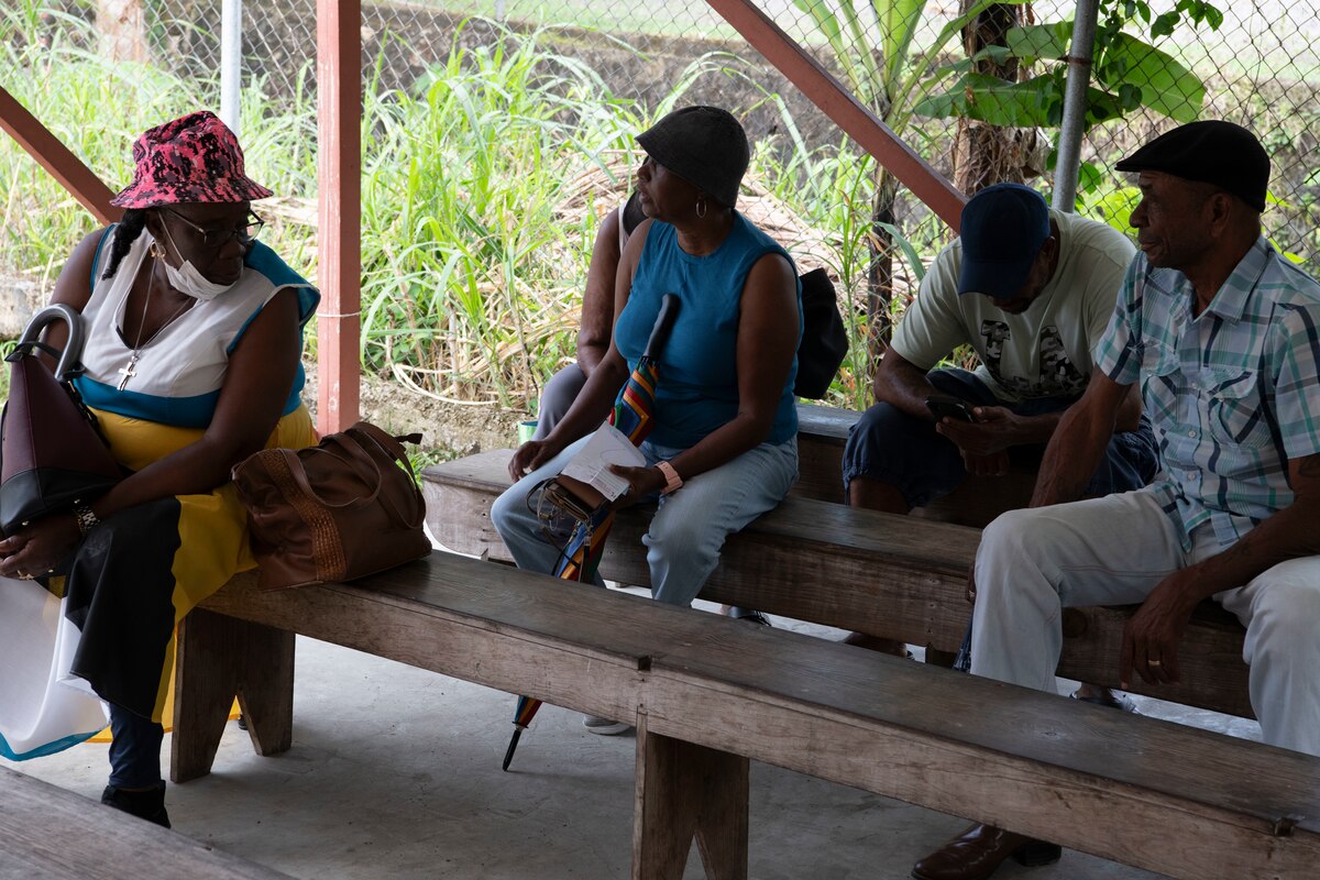 Local community members sitting on benches outside waiting for dental treatment.