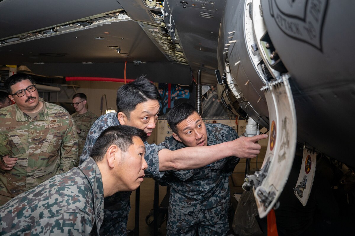 Japan Air Self-Defense Force members discuss the difference between a U S Air Force F 16 Fighting Falcon and an F 35 A Lightning 2 during an immersion tour at Misawa Air Base, Japan.