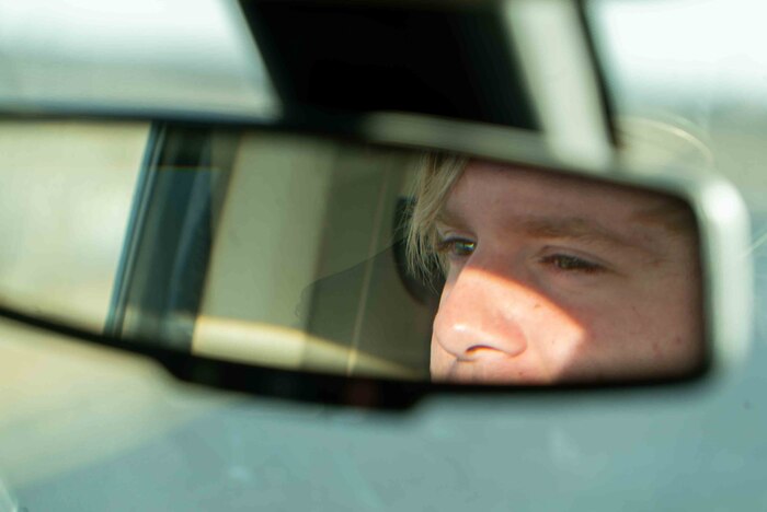 The reflection of Noah Baity is in the rearview mirror of his safety truck