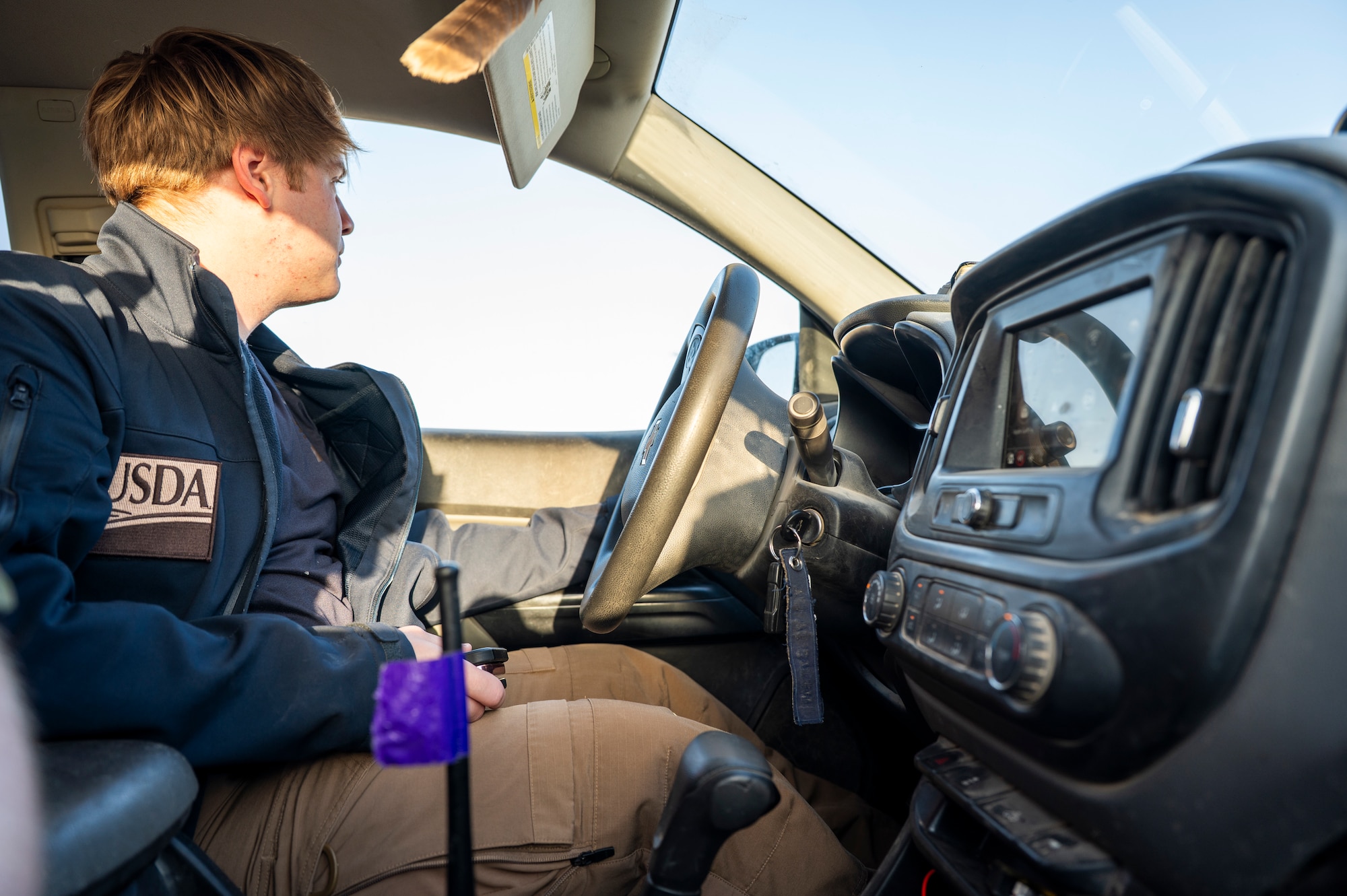 Noah Baity is in the driver's seat of his safety truck, driving alongside the flight line to check for birds