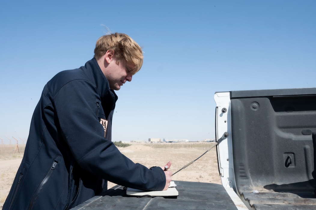 Noah Baity, left of frame, writes in his notebook on the back of the bed of his safety truck