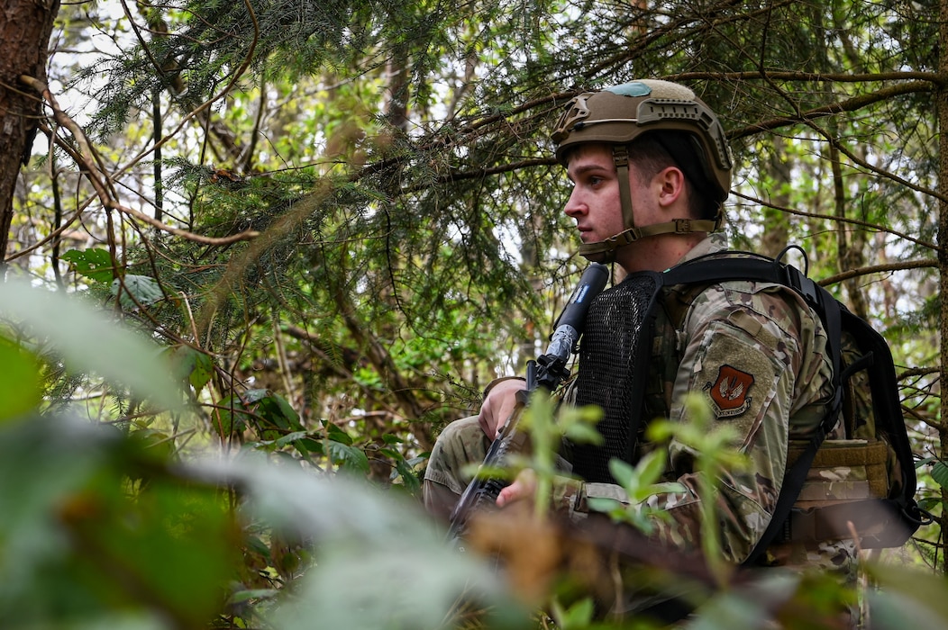 A military policeman pulls security in the woods.