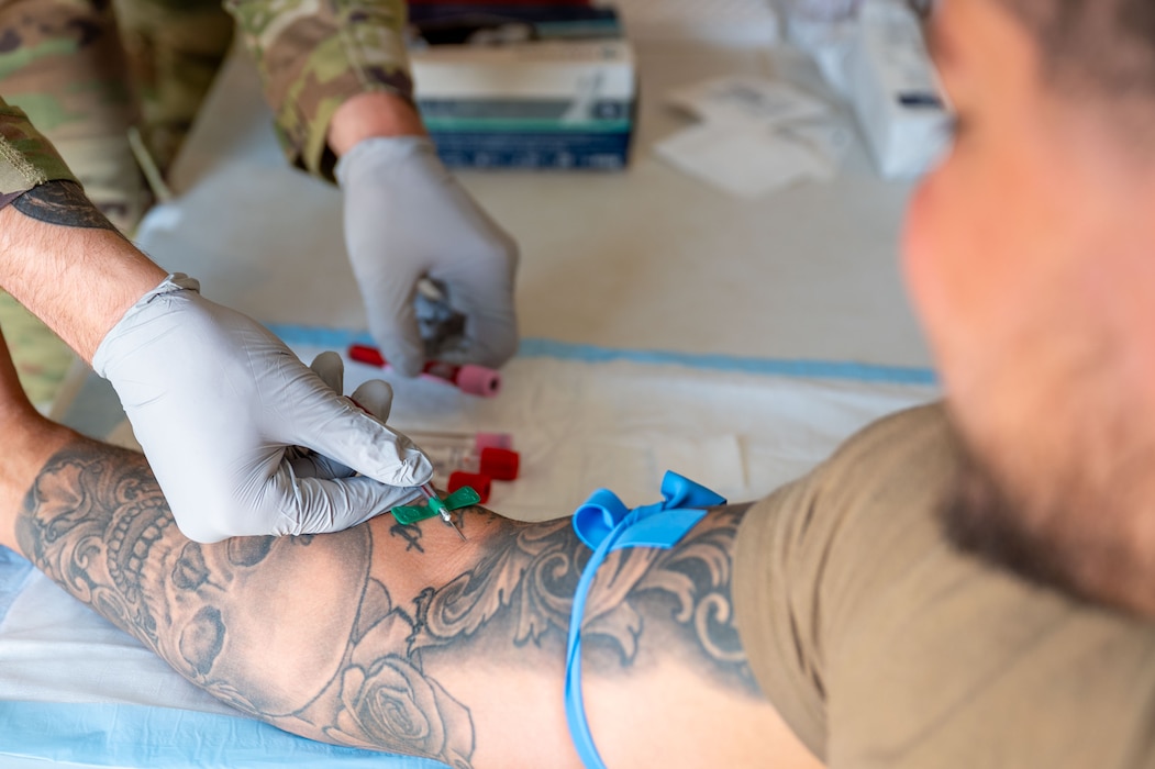 A blood sample is collected from a patient's arm via a winged infusion set.