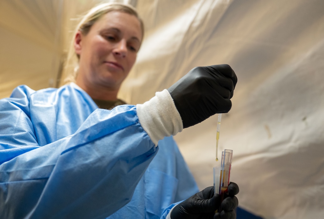 An Airman uses a pipette to separate a blood sample to be sent for testing.