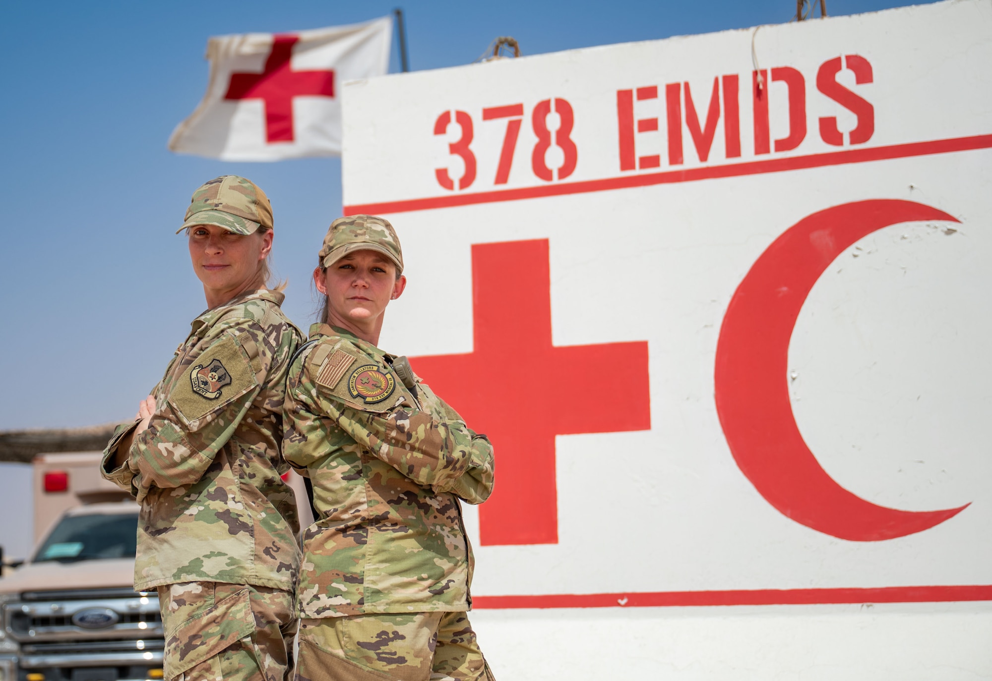 Two Airmen poses back-to-back for a photo.