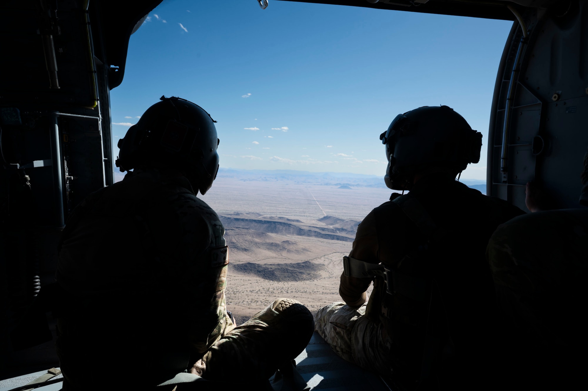 Two U.S. Air Force pararescuemen assigned to the 55th Rescue Squadron sit on an HH-60W Jolly Green II helicopter returning from a training sortie in Gila Bend, Arizona, April 29, 2025. The training sortie was conducted to maintain mission readiness, reinforce the Air Force’s core values of excellence and preparedness and ensure crews remain capable of executing critical operations anytime, anywhere. (U.S. Air Force photo by Airman Samantha Melecio)
