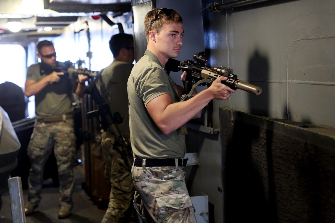 Coast Guardsmen aim weapons in close quarters.