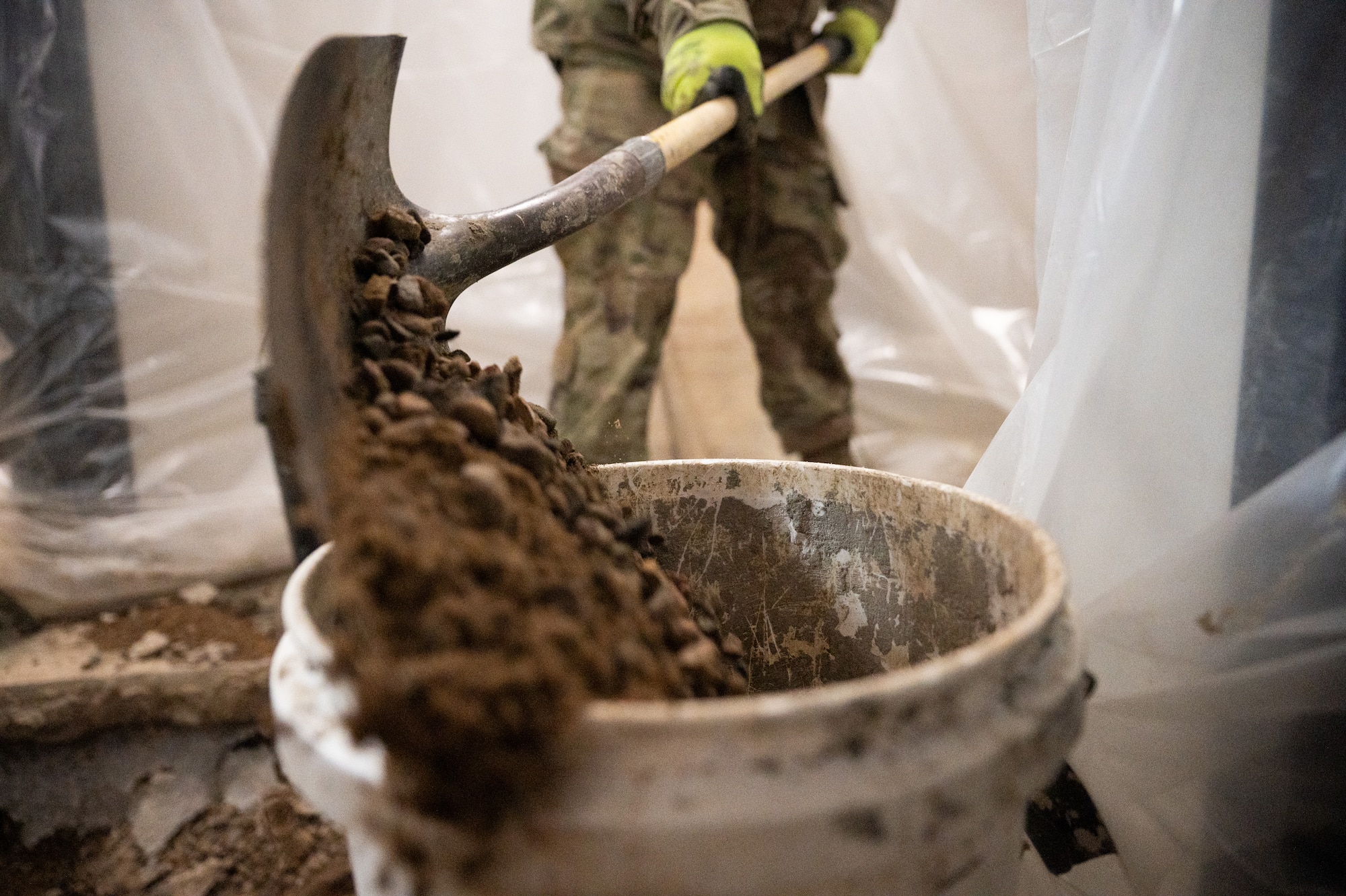 Broken-up concrete is shoveled into a bucket.