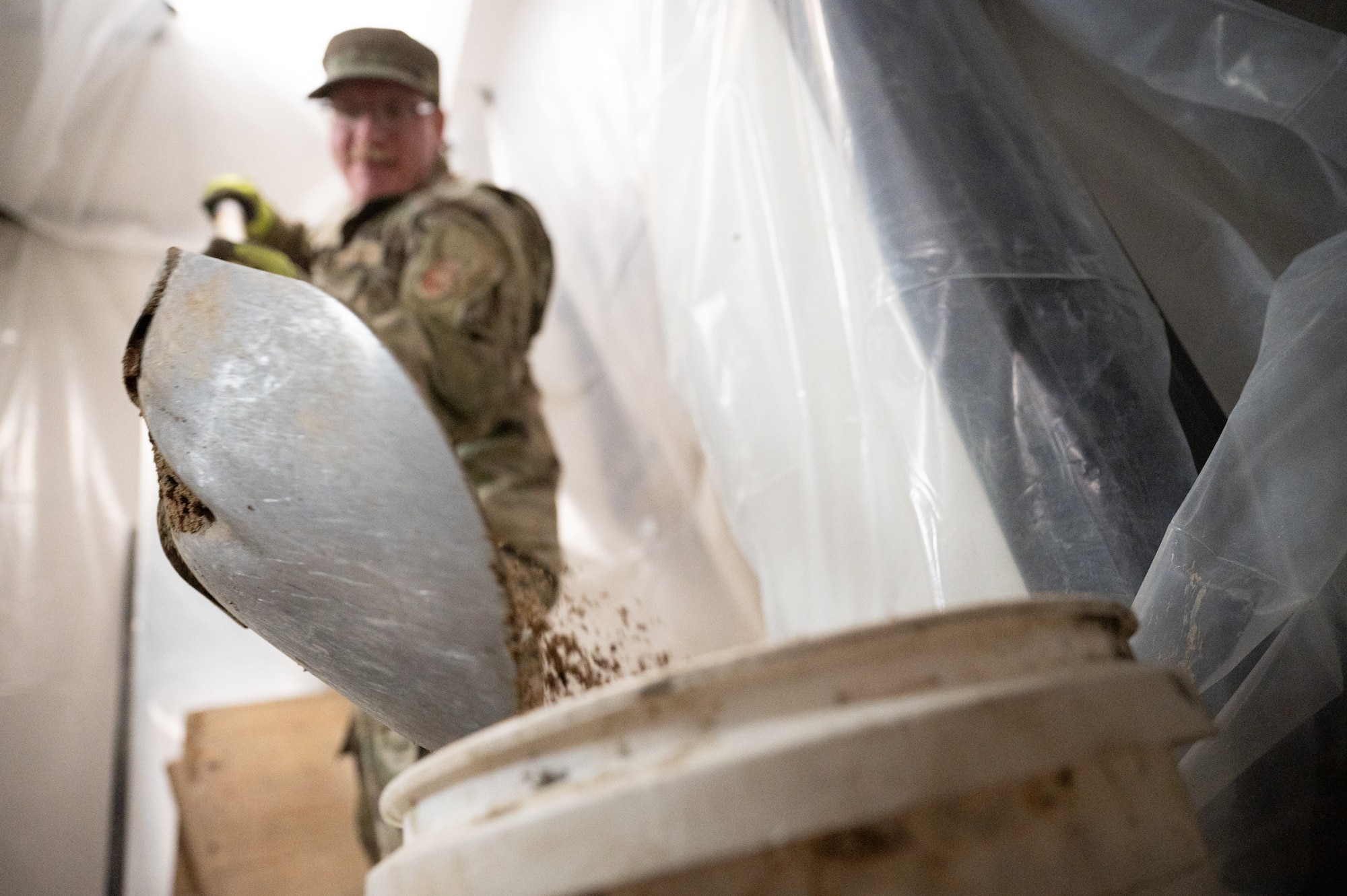 An Airman shovels broken-up concrete into a bucket.