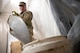 An Airman shovels broken-up concrete into a bucket.