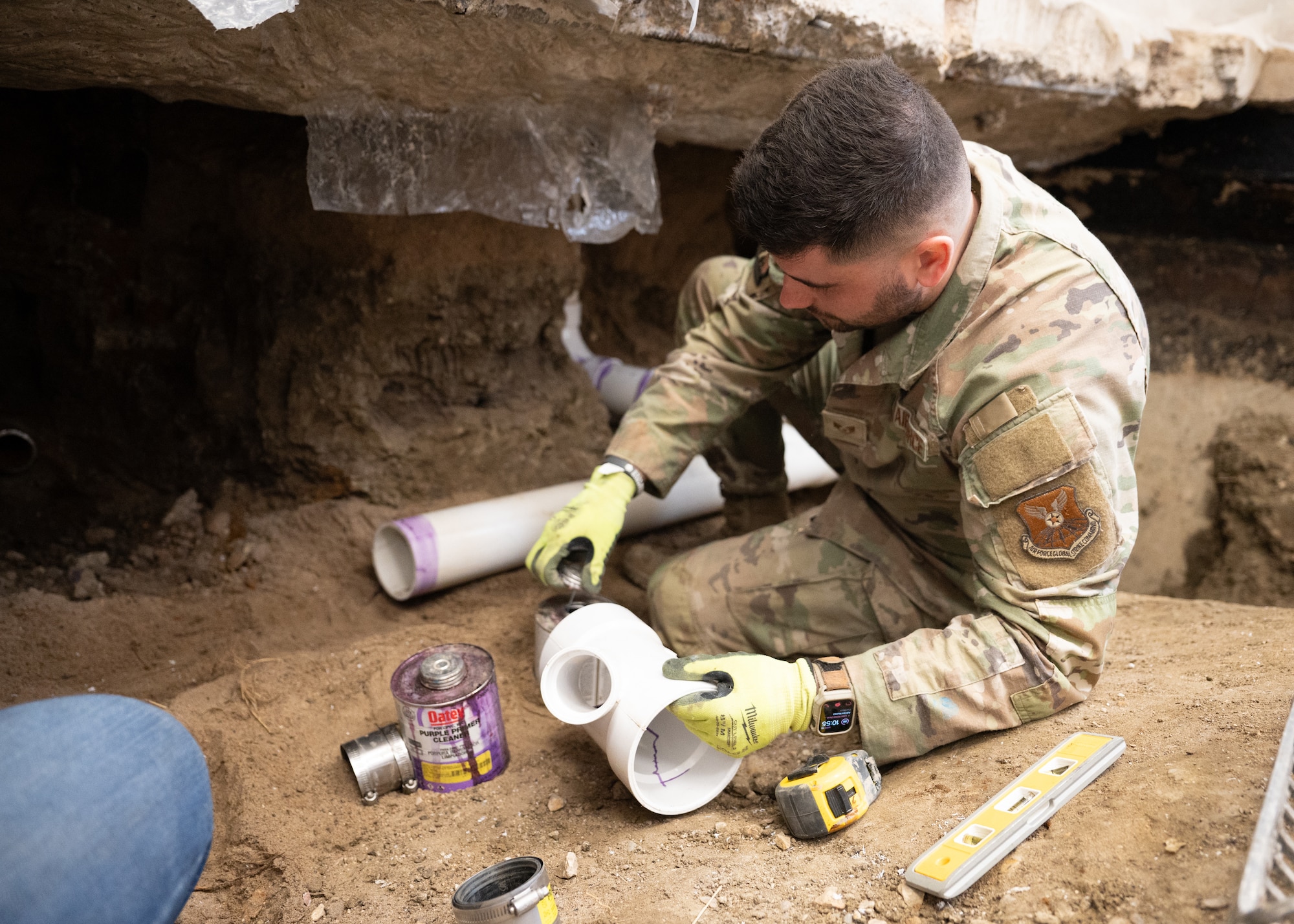 An Airman prepares PVC pipes inside a hand-excavated command suite.