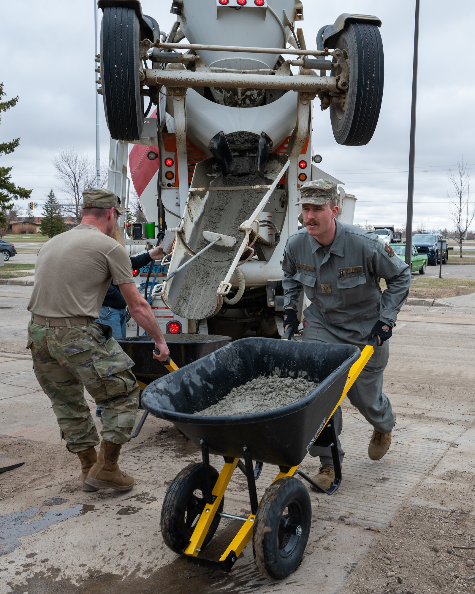 An Airman transports wet concrete in a wheelbarrow.