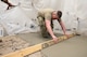 An Airman screeds concrete.