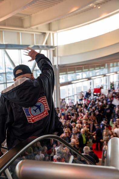 A veteran waves at the crowd during the Western North Dakota Honor Flight homecoming at Minot International Airport in Minot, N.D., April 28, 2025. Veterans were welcomed by family, friends and supporters after visiting Washington, D.C. memorials honoring their military service. (U.S. Air Force photo by Airman 1st Class Luis Gomez)