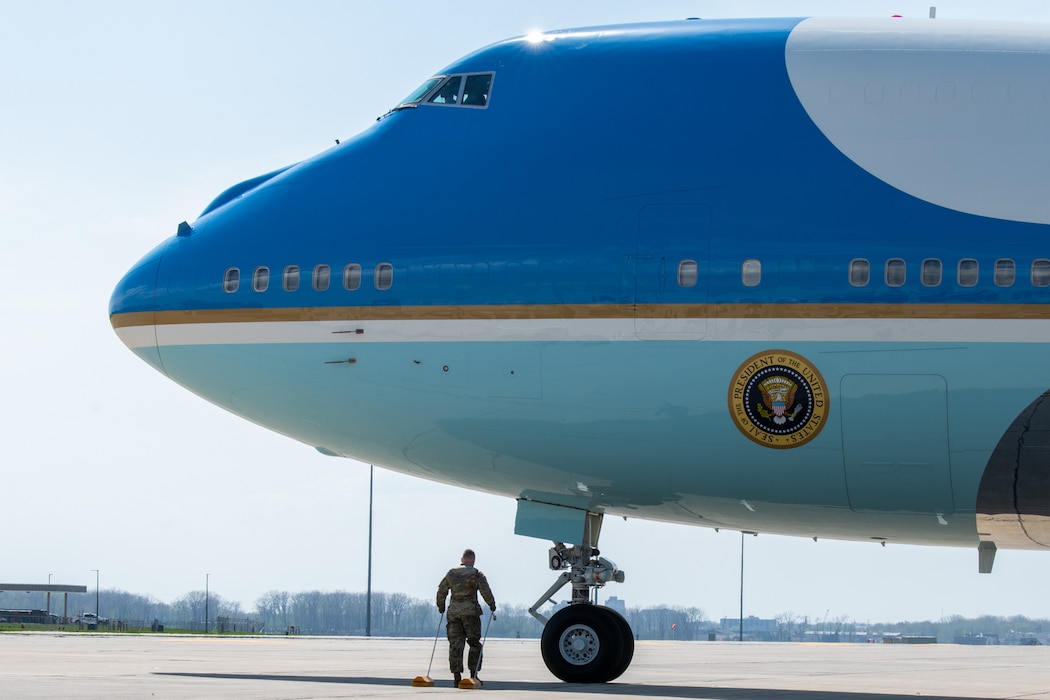Airman carries wood blocks in front of wheels of Air Force One.