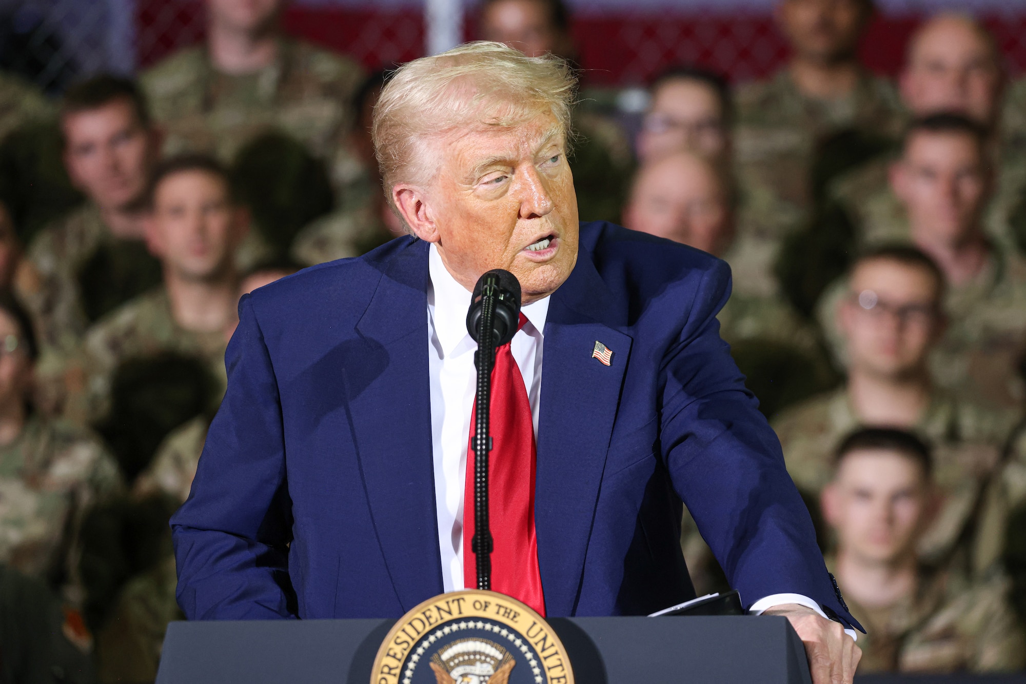 President speaks behind podium with uniformed servicemembers in the background