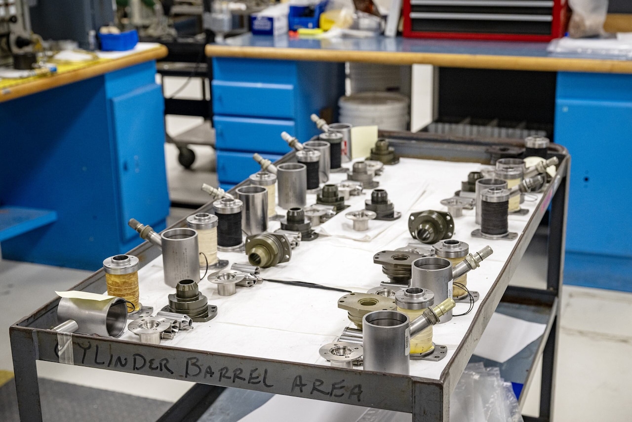 Several small metal parts are on a cart in a workshop.