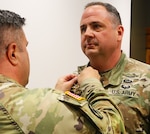 Col. Shawn Nokes, Commander of the 129th Regiment (Regional Training Institute) affixes the Legion of Merit on the collar of Command Sgt. Maj. Jonathan Genisio.
