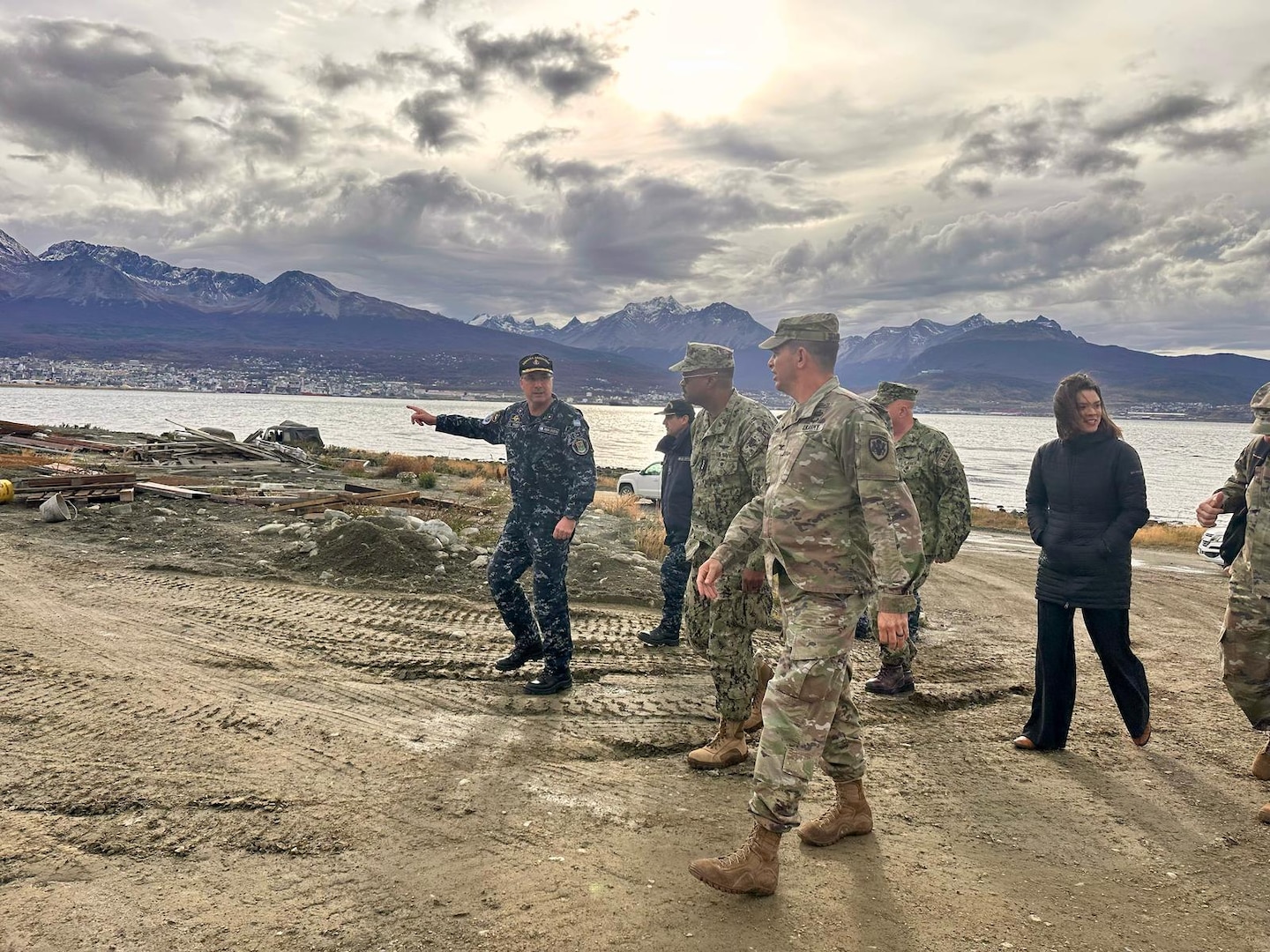 A group of military leaders walk with a waterway in the background.