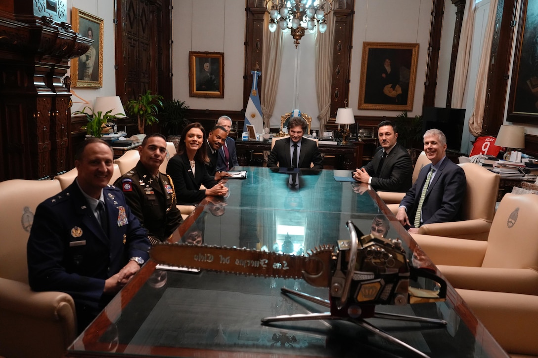 A group of people pose for a photo while seated around a long table.