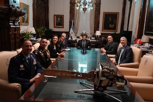 A group of people pose for a photo while seated around a long table.