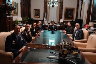 A group of people pose for a photo while seated around a long table.