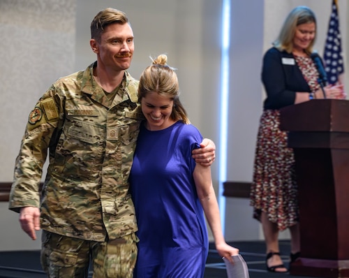 A service member escorts his wife offstage.