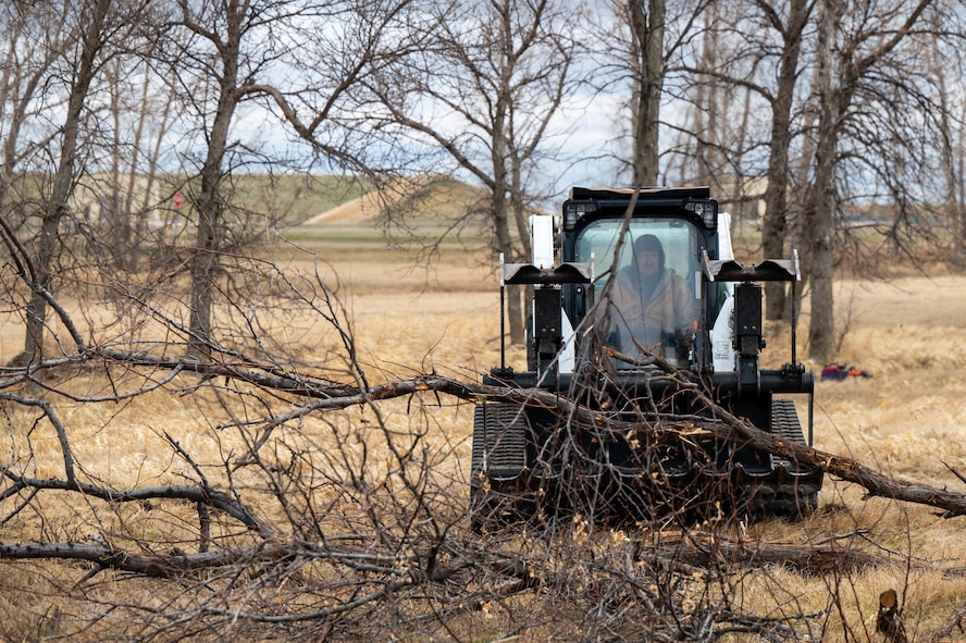 U.S. Air Force Wildland Fire Branch crew member collects Russian Olive trees that were cut down on Minot Air Force Base, North Dakota, April 22, 2025. The Wildland Branch helps protect Air Force personnel and property from wildfires by clearing away dangerous plants and other things that can easily catch fire. (U.S. Air Force photo by Senior Airman Alexander Nottingham)