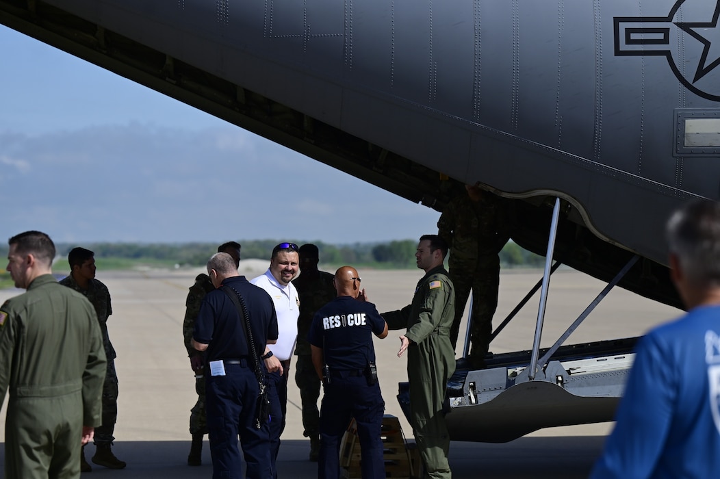 A group of people gather behind an airplane.